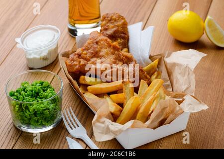 Piselli verdi, pesce e patatine fritte. Pranzo gustoso e nutriente Foto Stock