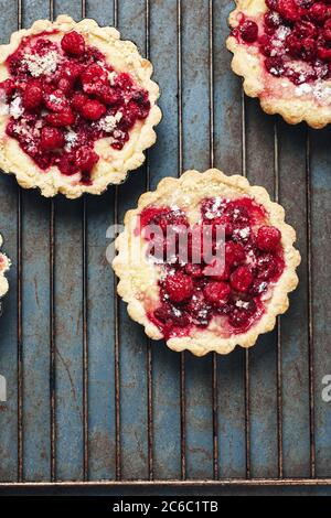 Mini torte al forno con lamponi su una vecchia teglia, vista dall'alto. Foto Stock