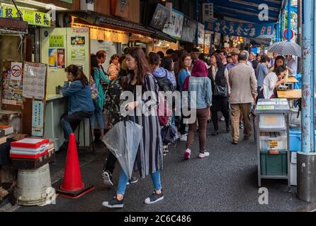 Folla di persone che passeggiano al mercato esterno di Tsukiji, lungo la strada stretta, Tokyo, Giappone Foto Stock