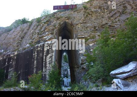 ingresso naturale ad arco di una cava di marmo ex nelle alpi apuane dell'appennino Foto Stock