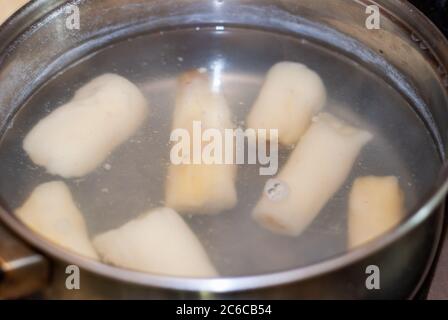 Cottura manioca in una pentola con acqua bollente, esculenta Manihot. Manioca, chiamata anche mandioca, yuca, balinghoy, mogo, mandioca, kamoteng kahoy, tapioc Foto Stock