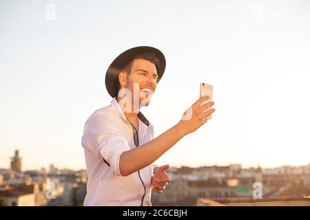 Giovane cantante che si esibisce su reti sociali sul tetto di un edificio in città Foto Stock