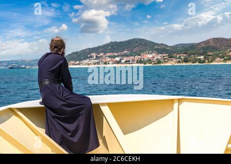 Il vecchio monaco guarda le montagne Athos su una nave in una giornata estiva Foto Stock