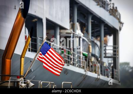 La bandiera americana di un rimorchiatore della Marina statunitense che spinge una nave al suo molo a Yokouska, Giappone. Foto Stock