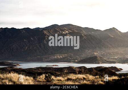 Splendida vista dal campo al lago con la catena montuosa delle Ande alle spalle con la luce soffusa dell'alba in un giorno d'autunno Foto Stock