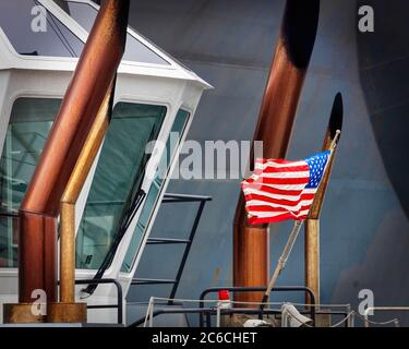 La bandiera americana di un rimorchiatore della Marina statunitense che spinge una nave al suo molo a Yokouska, Giappone. Foto Stock