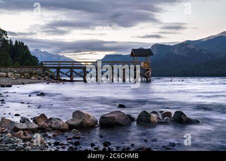 Paesaggio Patagonia con un molo in legno su un lago roccioso in una tranquilla giornata nuvolosa Foto Stock