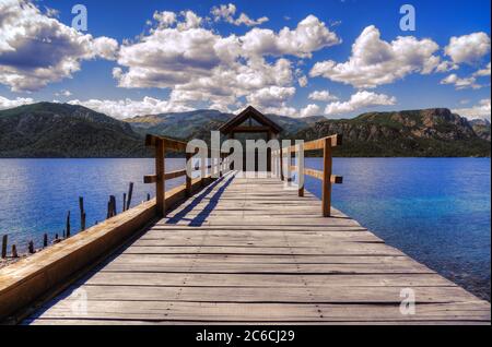 Molo in legno sul lago con le montagne dietro in una giornata nuvolosa Foto Stock