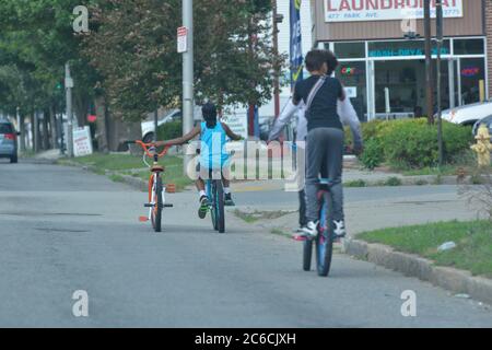 Worcester, Massachusetts, Stati Uniti. 8 luglio 2020. I ciclisti aiutano un amico su Park Avenue la cui moto ha una gomma piatta. I bambini della città interna si trovano a dover affrontare il caldo estivo e le restrizioni del Covid-19, navigando per le strade del centro di Worcester, noto come il cuore del Commonwealth del Massachusetts, e due volte nominata una città tutta americana. Credit: Kenneth Martin/ZUMA Wire/Alamy Live News Foto Stock