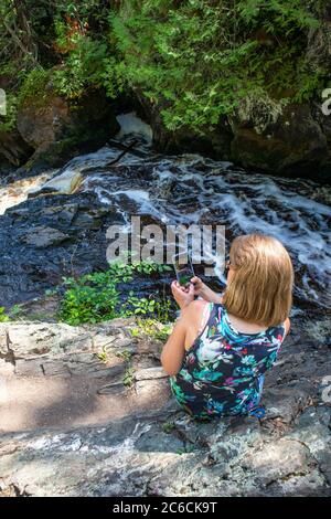 Donna che scattano una foto di un fiume con il suo smartphone, verticale Foto Stock