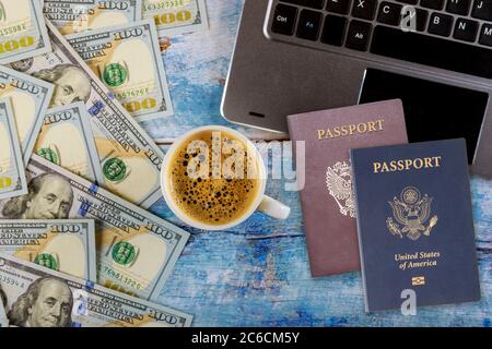 Scrivania da ufficio con computer portatile passaporto americano e russo, caffè espresso e dollari USA Foto Stock