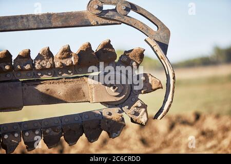 Primo piano di una catena di scavatrincee in movimento che si prepara a scavare una trincea nello sporco Foto Stock