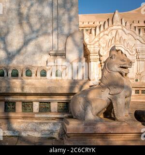 Una vista di profilo di una statua in pietra scolpita di un chinthe (leone) al tempio buddista di Ananda a Yangon, Myanmar Foto Stock