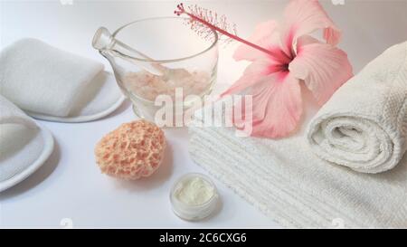 Ambiente Spa e composizione di sfondo Spa con fiore rosa ibisco su sfondo bianco. Banner. Spazio di copia. Asciugamano, candele, fiori, pietre. Massa Foto Stock