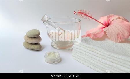 Ambiente Spa e composizione di sfondo Spa con fiore rosa ibisco su sfondo bianco. Banner. Spazio di copia. Asciugamano, candele, fiori, pietre. Massa Foto Stock