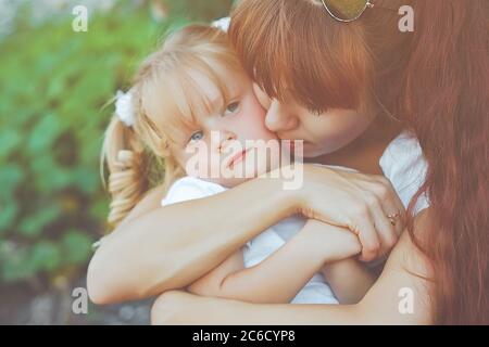 madre si siede con sua figlia in natura accanto alle foglie verdi Foto Stock