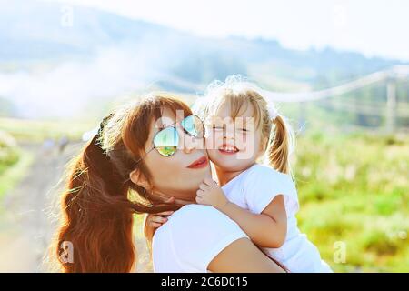 madre si siede con sua figlia in natura accanto alle foglie verdi Foto Stock