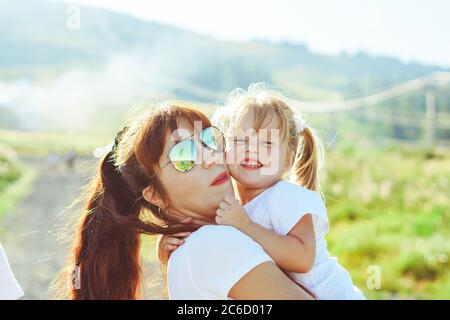 madre si siede con sua figlia in natura accanto alle foglie verdi Foto Stock