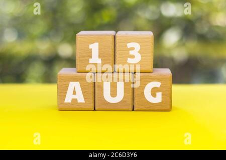 Cubetti di legno con testo 13 AGO. 13 agosto - Giornata internazionale dei lefthanders. Sfondo verde naturale sfocato. Ora legale. Foto Stock