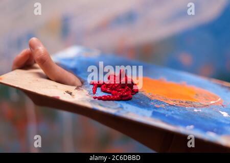 Donna pittore che tiene la tavolozza di legno con vernice rossa. Pittura moderna su tela, creativo, contemporaneo e di successo artista di arte di disegno capolavoro Foto Stock