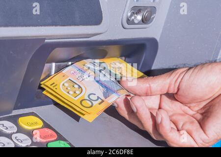 Prendendo diverse banconote australiane da 50 dollari da un bancomat. Foto Stock