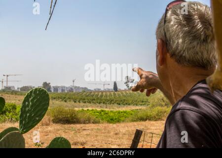 lo sviluppo urbano sta strisciando e consumando terreni arabili. Il contadino punta alla nuova città che viene costruita vicino ai suoi campi. Fotografato a Haniel [a m Foto Stock