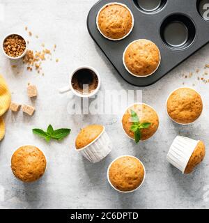 Muffin al caramello alla vaniglia in tazze di carta su sfondo di cemento, vista dall'alto. Cottura muffin processo, ricetta alimentare Foto Stock