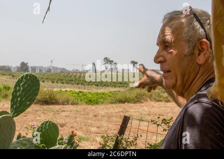 lo sviluppo urbano sta strisciando e consumando terreni arabili. Il contadino punta alla nuova città che viene costruita vicino ai suoi campi. Fotografato a Haniel [a m Foto Stock