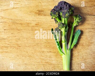 Un bastone di broccoli porpora su una tagliere di legno con spazio per la copia Foto Stock