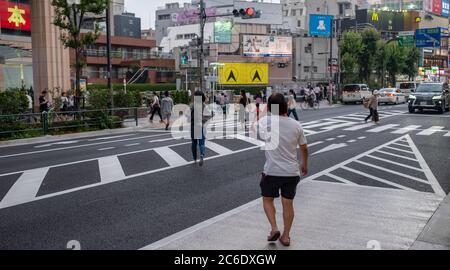 Pedone che attraversa la strada del quartiere di Sangenjaya, Tokyo, Giappone al tramonto. Foto Stock