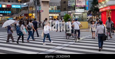 Pedone che attraversa la strada del quartiere di Sangenjaya, Tokyo, Giappone al tramonto. Foto Stock