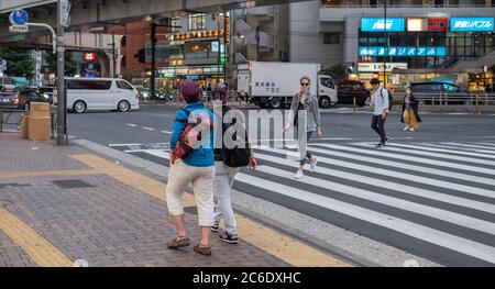 Pedone che attraversa la strada del quartiere di Sangenjaya, Tokyo, Giappone al tramonto. Foto Stock