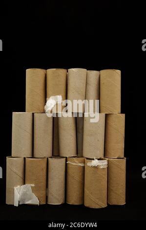 I rotoli di carta igienica vuoti si impilano su uno sfondo nero Foto Stock