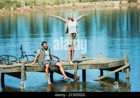 Donna esuberante con braccia distese sul molo sopra il lago Foto Stock