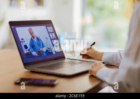 Donna videoconferenza con medico al portatile Foto Stock