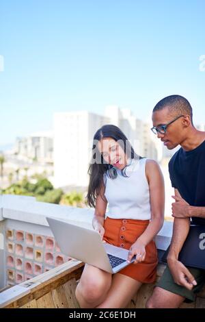 Giovani uomini d'affari con computer portatile che lavorano sul tetto urbano Foto Stock