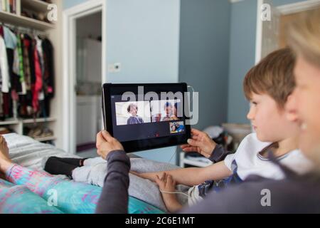 Chat video con la famiglia con tablet digitale a letto Foto Stock