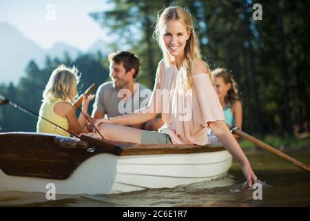 Donna sorridente con la famiglia in barca a remi sul lago Foto Stock