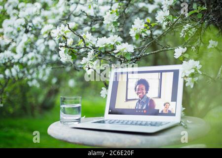 I colleghi stanno chattando video sullo schermo del laptop in giardino Foto Stock