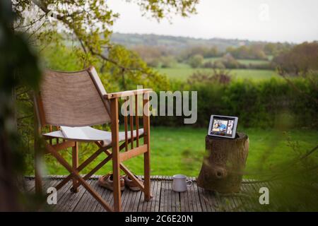 Chat video degli amici sullo schermo del tablet digitale su un patio idilliaco Foto Stock