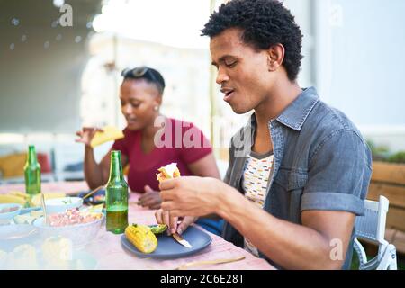 Giovane uomo che mangia pranzo taco al tavolo del patio Foto Stock