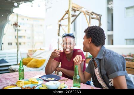 Felice giovane coppia che mangia il pranzo al tavolo del patio Foto Stock