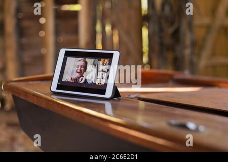 Chat video degli amici sullo schermo del tablet digitale su una barca di legno Foto Stock