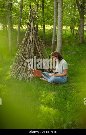 Donna con computer portatile rilassante in branca teepee in legno Foto Stock