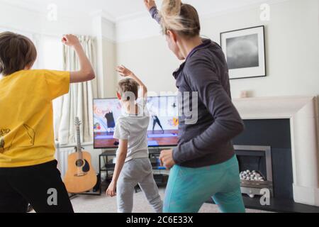 Madre e figli che si esercitano in TV in soggiorno Foto Stock