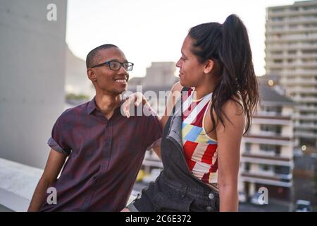 Una giovane coppia felice che parla sul balcone urbano sul tetto Foto Stock