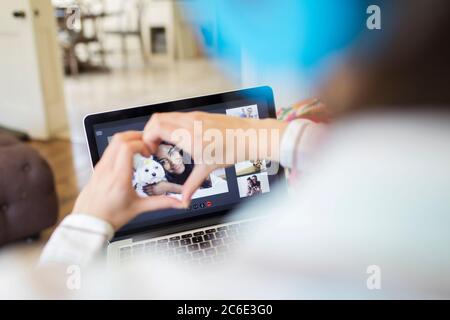 Ragazza adolescente che crea forma a cuore con le mani sopra la chat video sul laptop Foto Stock