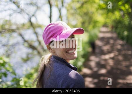 Ritratto felice donna escursioni su sentiero soleggiato Foto Stock