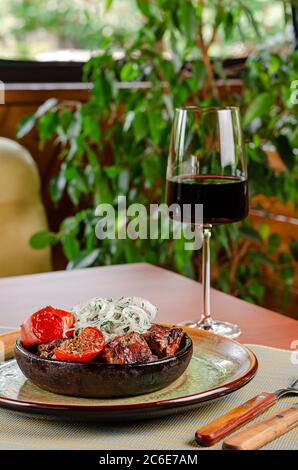 Tradizionale carne georgiana glillata su spiedini con pomodori e cipolle marinate servita in ciotola rustica. Concetto di menu del ristorante Foto Stock