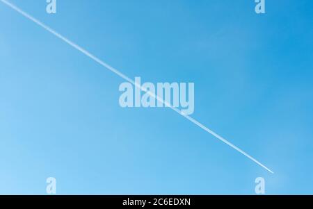 Jet aereo che vola e il suo contrail su cielo blu Foto Stock